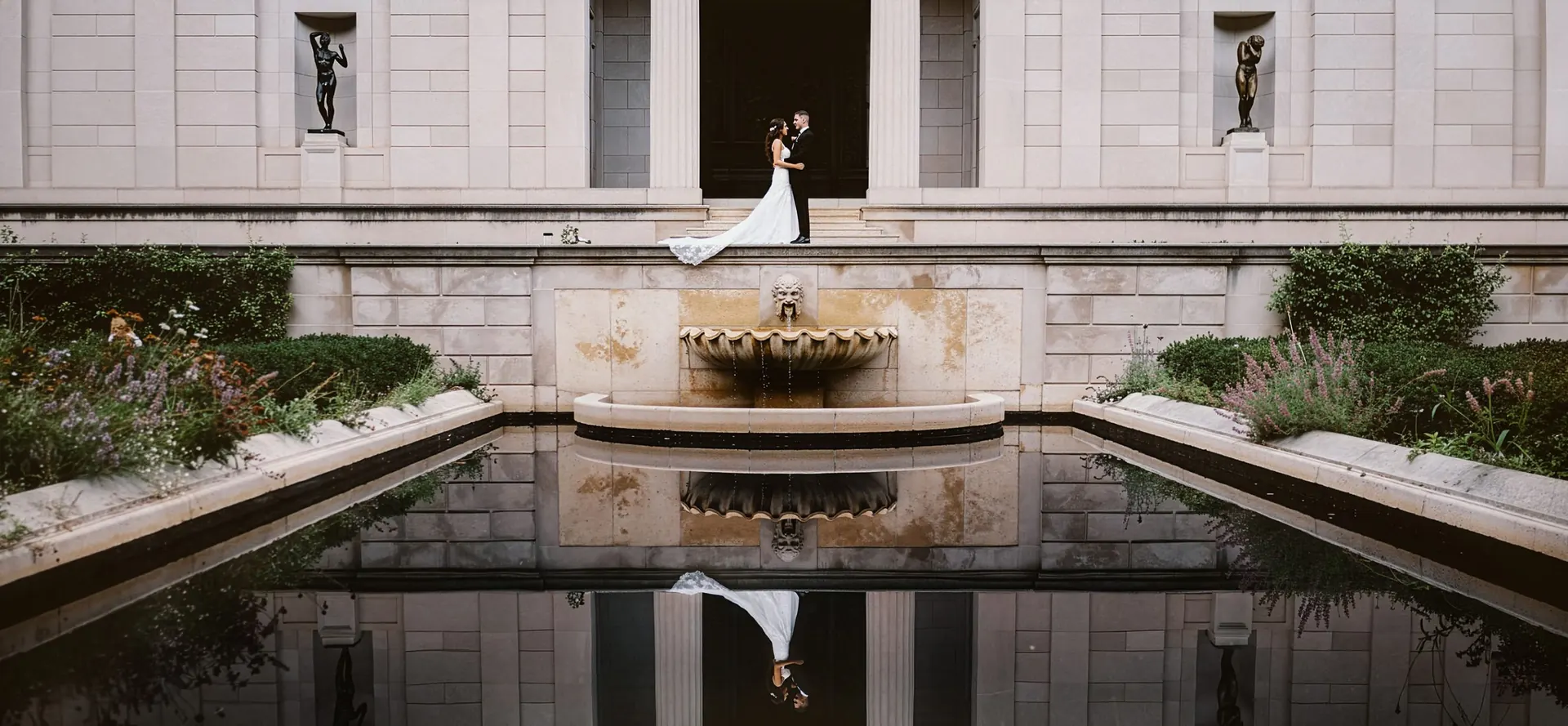 Bride and groom on the steps of the Rodin Museum in Philadelphia above the reflecting pool and fountain