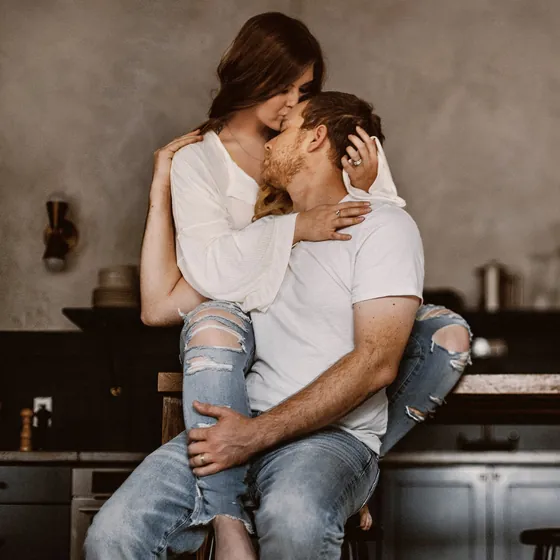 Couple embracing on a kitchen stool during an at-home engagement session