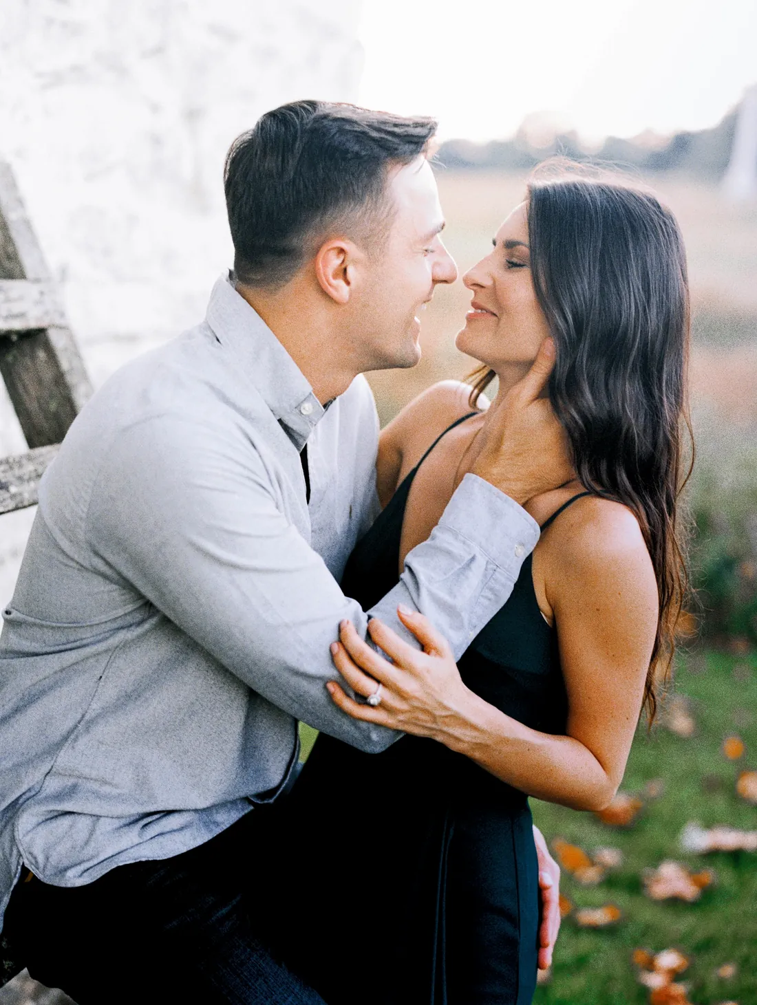 Engaged couple leaning in for a kiss outdoors in autumn
