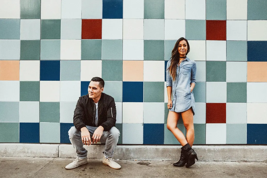 Engaged couple posing in front of a colorful tiled wall