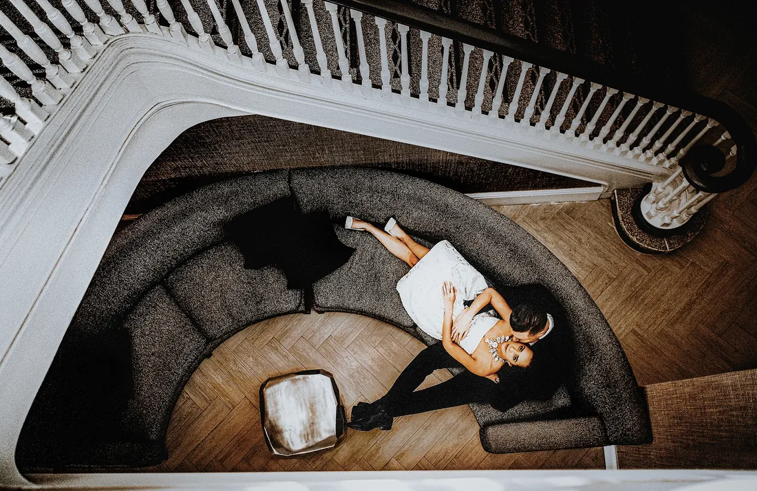 Engaged couple lying on a curved sofa, seen from above
