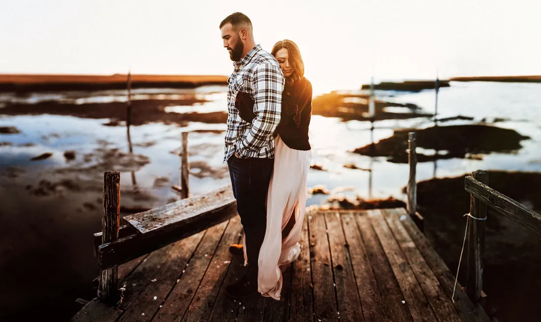 Engaged couple on a weathered dock at sunset