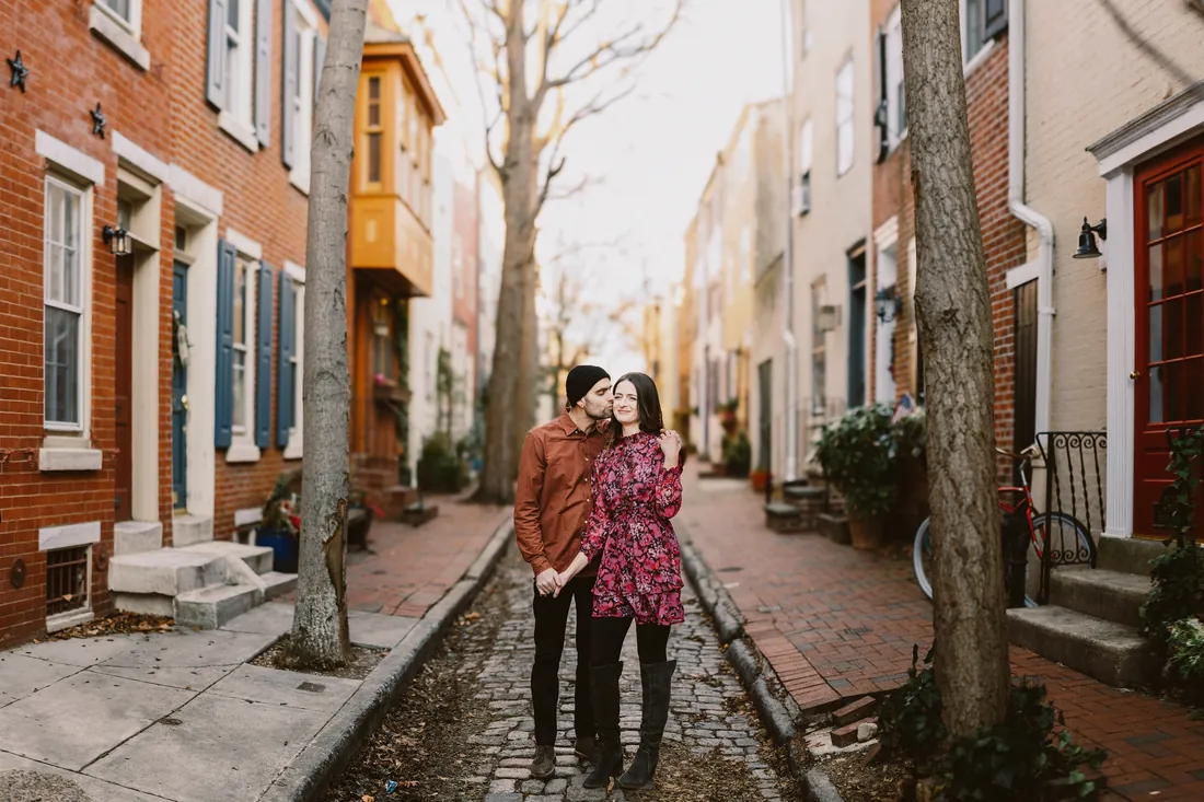 Engaged couple on a historic cobblestone street lined with brick row homes