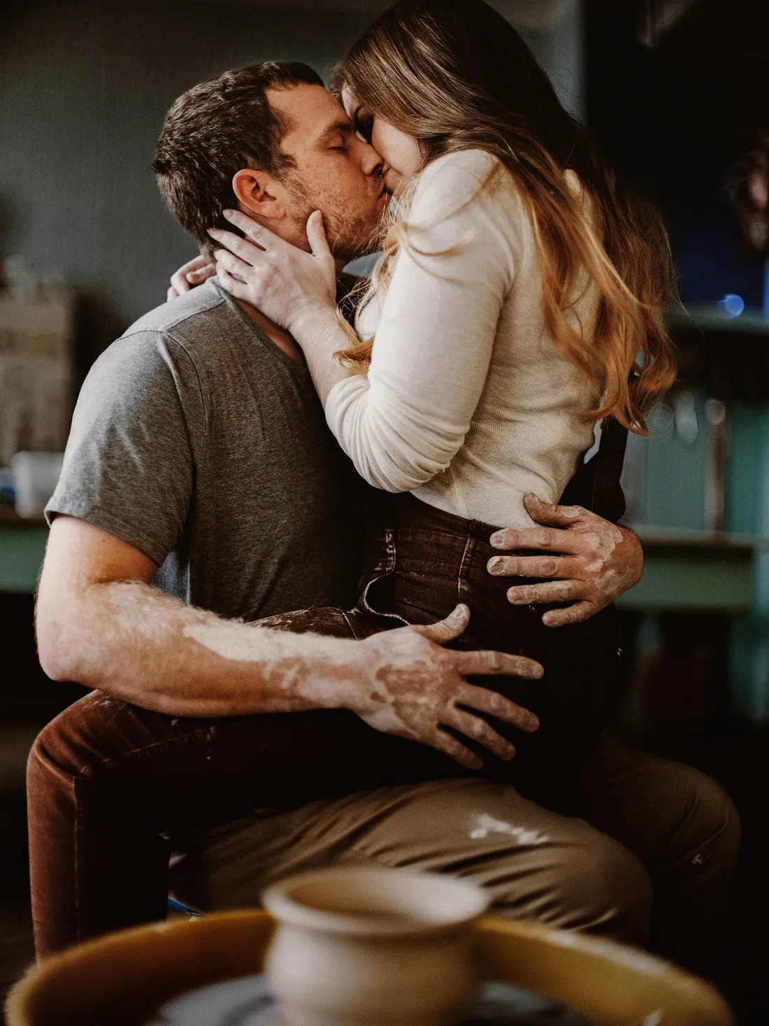 Engaged couple kissing in a pottery studio