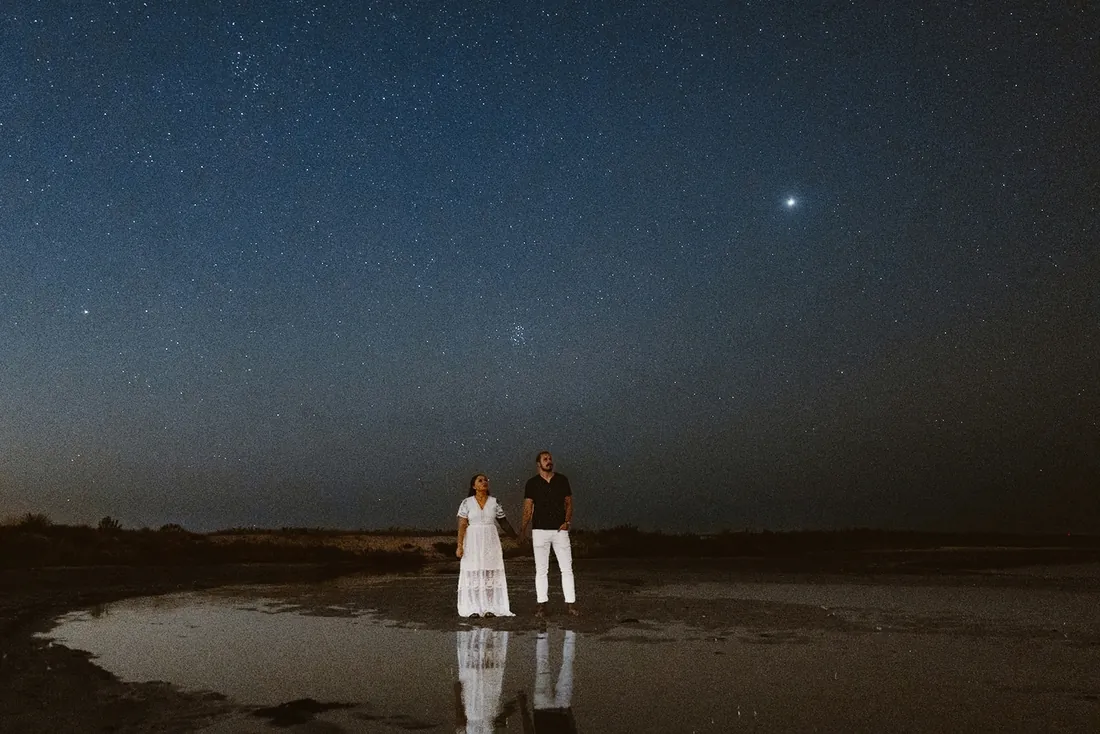 Engaged couple under a starry sky by the water at Barnegat Lighthouse on Long Beach Island, NJ