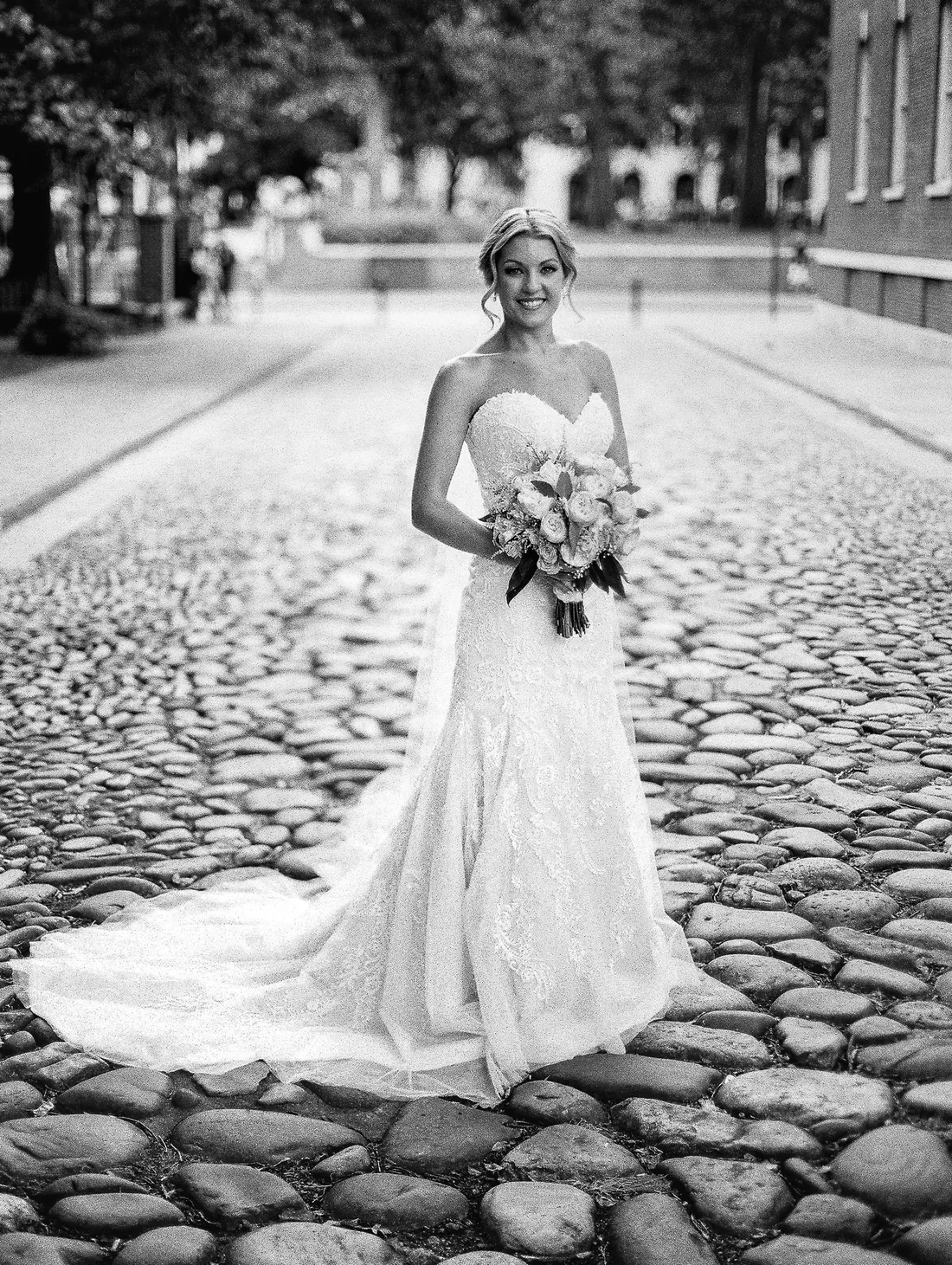 Black and white film portrait of a bride on a cobblestone street