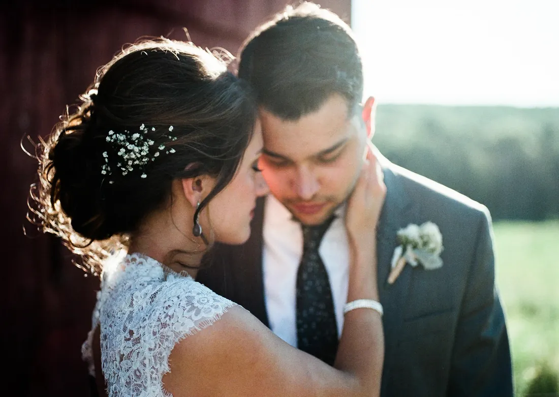 Film photograph of a bride touching her groom's face in warm golden light
