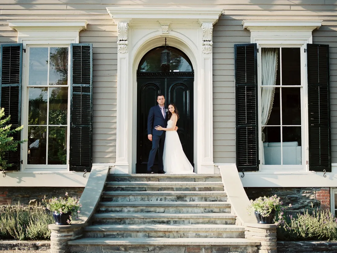 Film photograph of a bride and groom on the front steps of a historic home