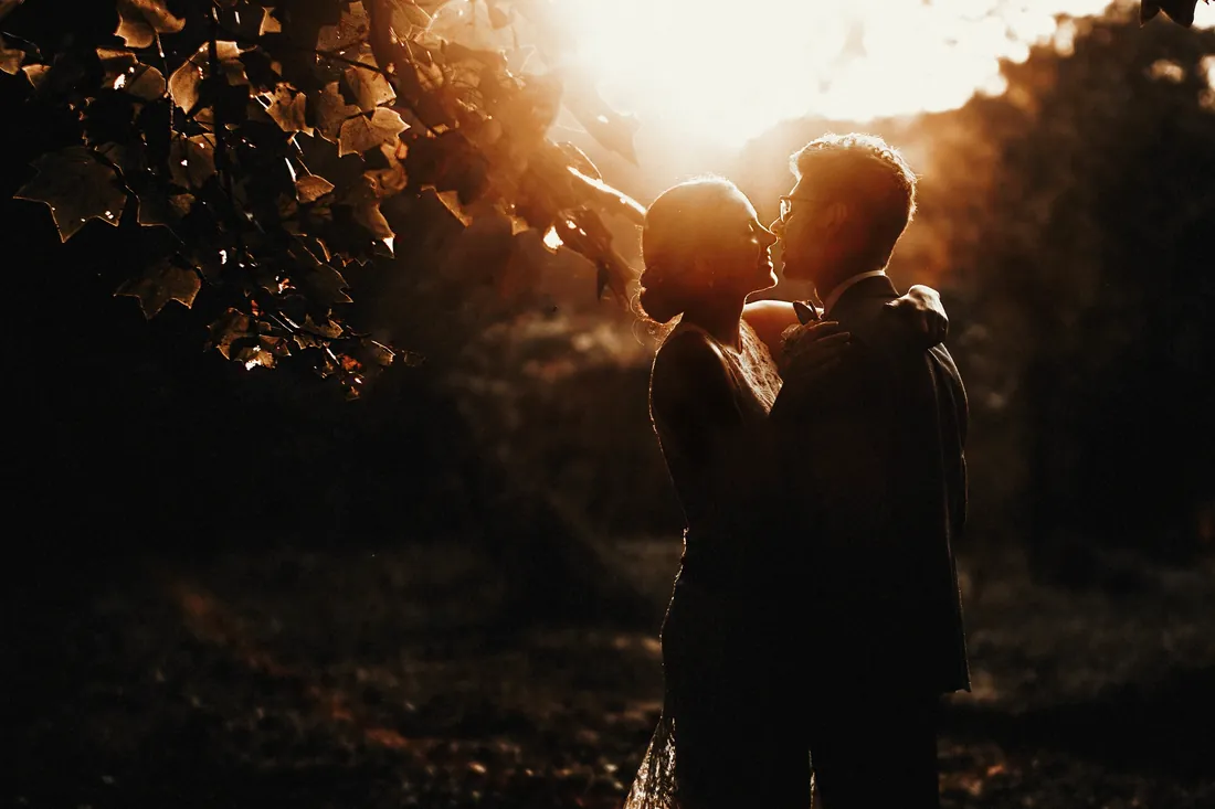 Bride and groom kissing in warm backlight at sunset