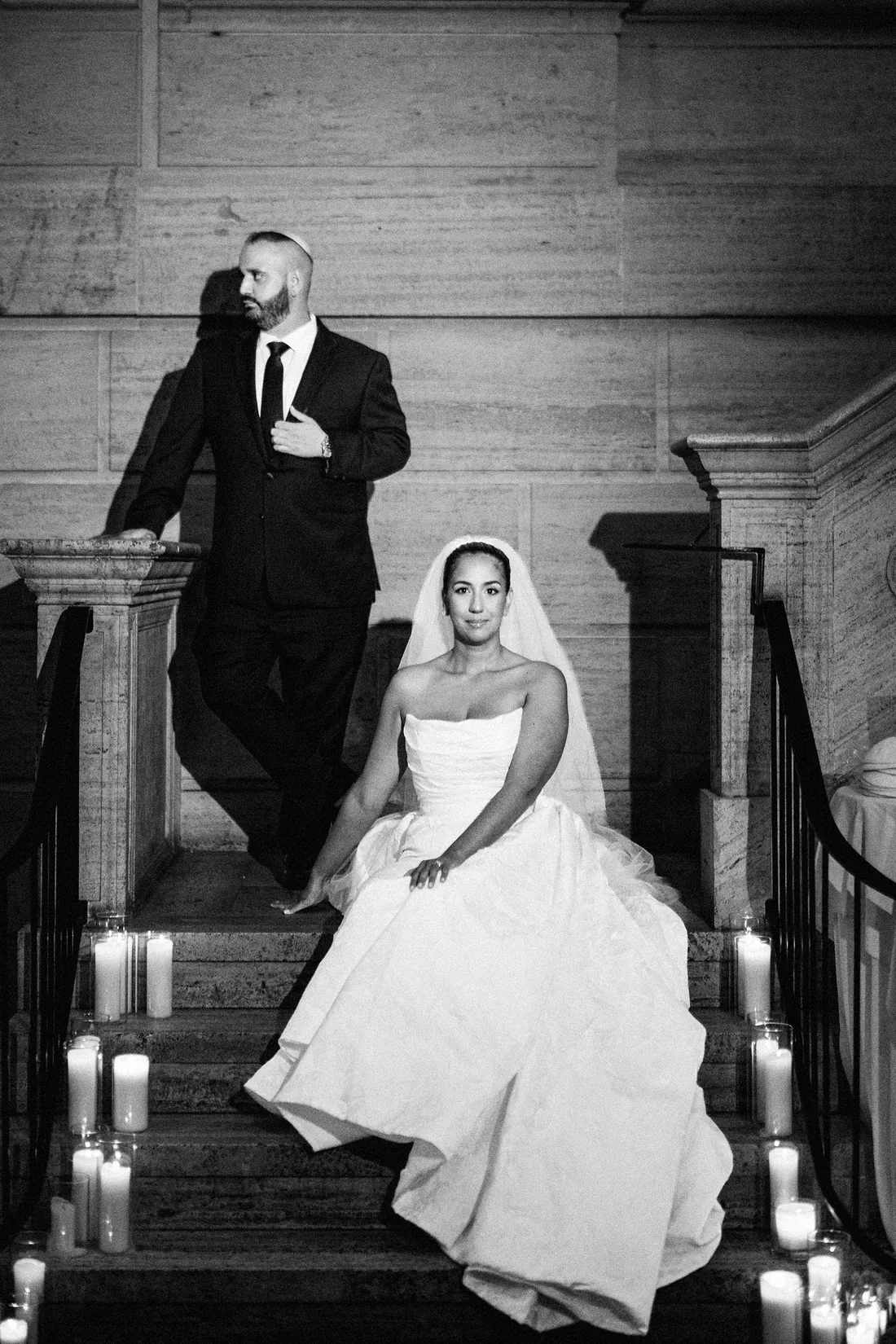 Black and white photo of a bride and groom on a candlelit staircase