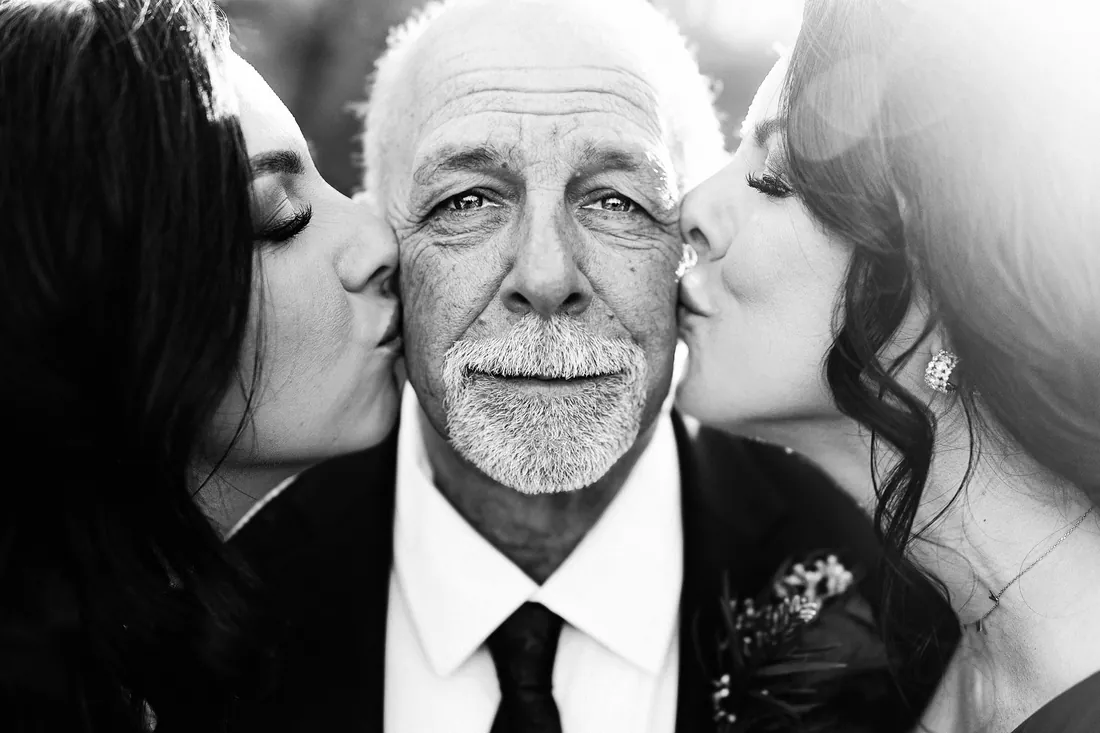 Black and white photo of a father being kissed on both cheeks