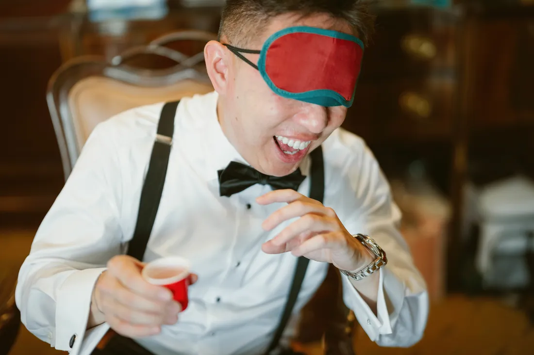Blindfolded groom laughing during a reception game