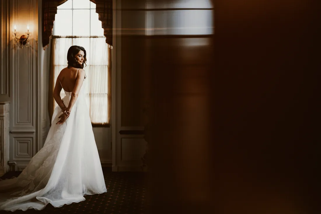 Bride standing by a tall window in an elegant room