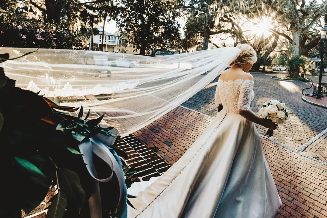 Bride with a long cathedral veil under oak trees