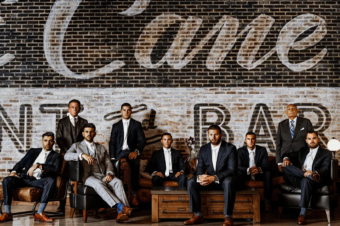 Groom and groomsmen in front of a painted brick wall