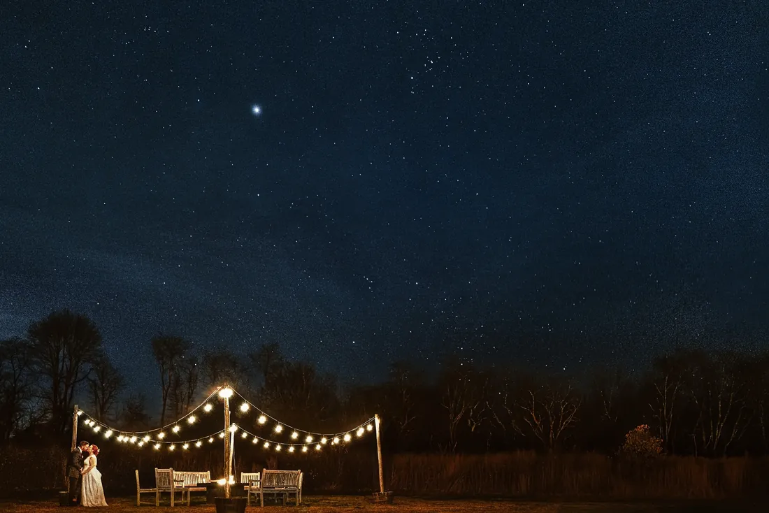String lights glowing under a starry sky at an outdoor reception