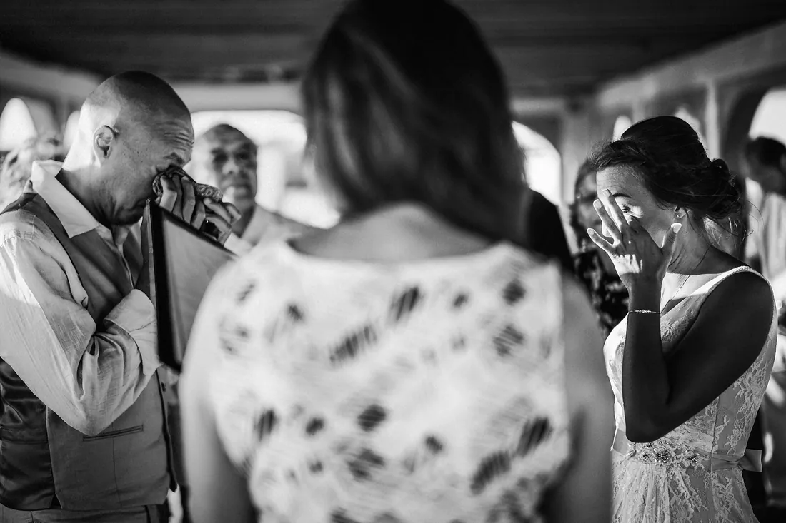 Black and white photo of family wiping away tears with the bride