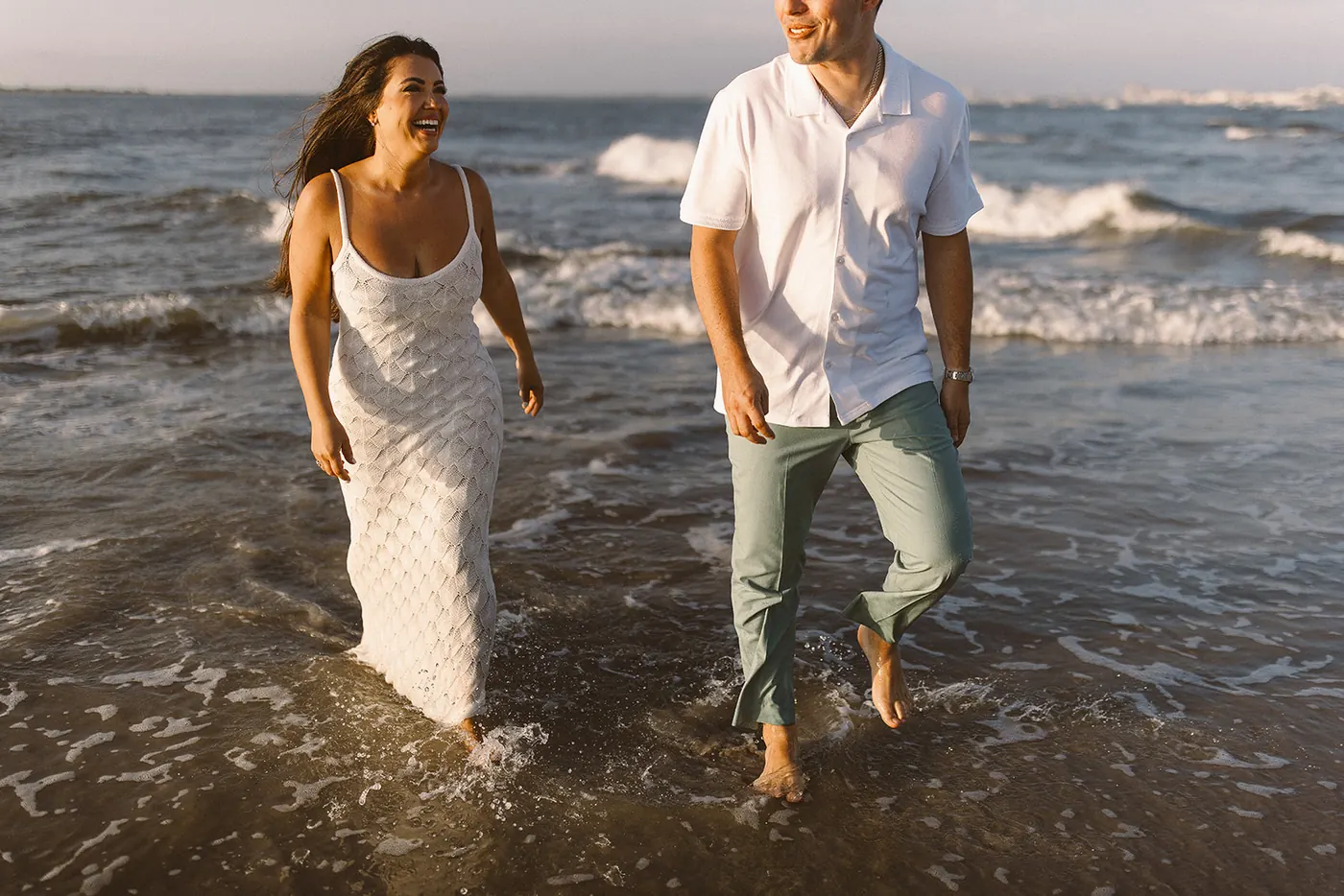 Branon and Celeste laughing as they walk through the waves in Ocean City, NJ, near the Longport bridge