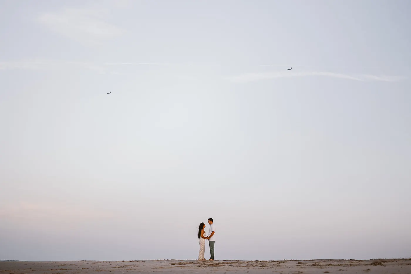 Branon and Celeste small on the wide beach at dusk in Ocean City, NJ, near the Longport bridge