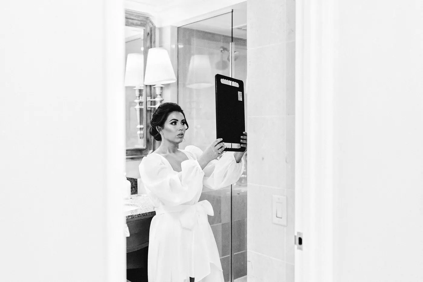 Black and white photo of Celeste checking her makeup in a mirror
