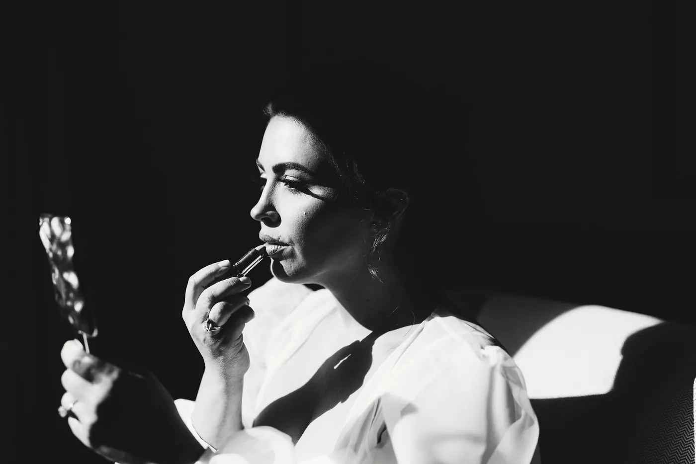 Black and white photo of Celeste putting on lipstick