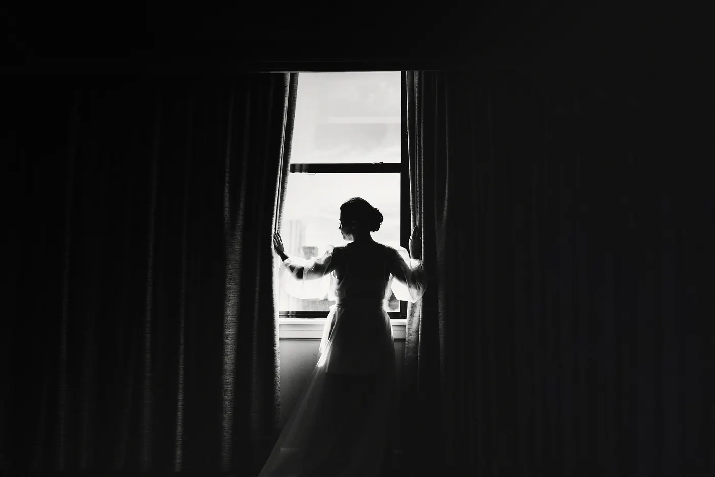 Black and white silhouette of Celeste in her gown at the window