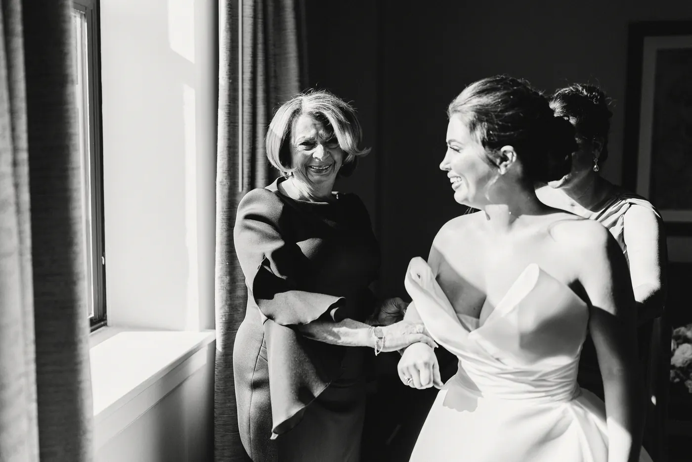 Black and white photo of Celeste laughing with her family as she gets dressed
