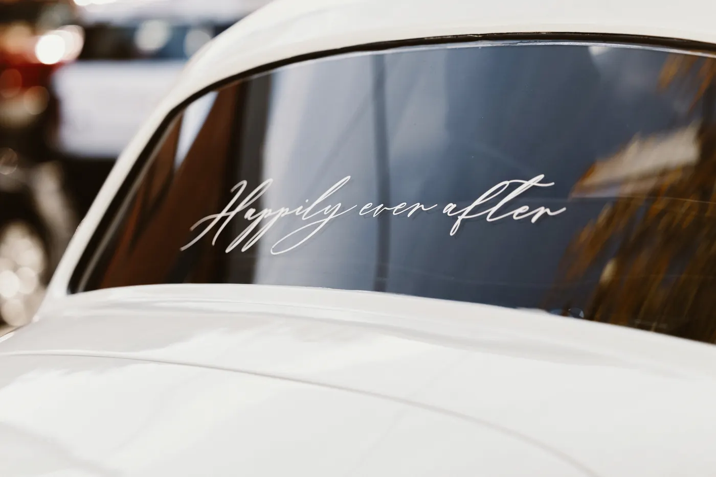 Happily ever after written on the window of a white vintage car
