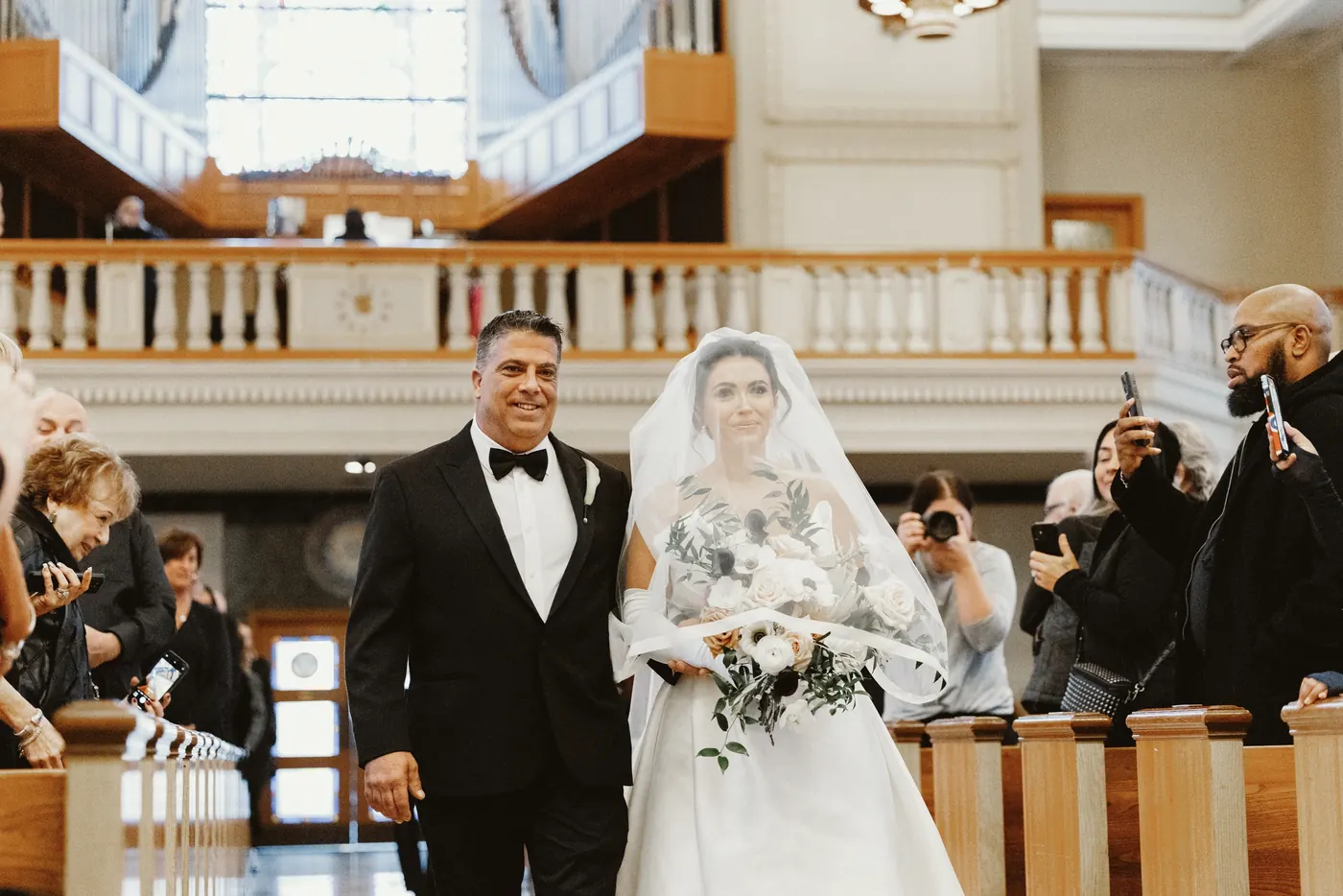 Celeste's father walking her down the aisle during their ceremony at Saint Monica Roman Catholic Church in South Philadelphia