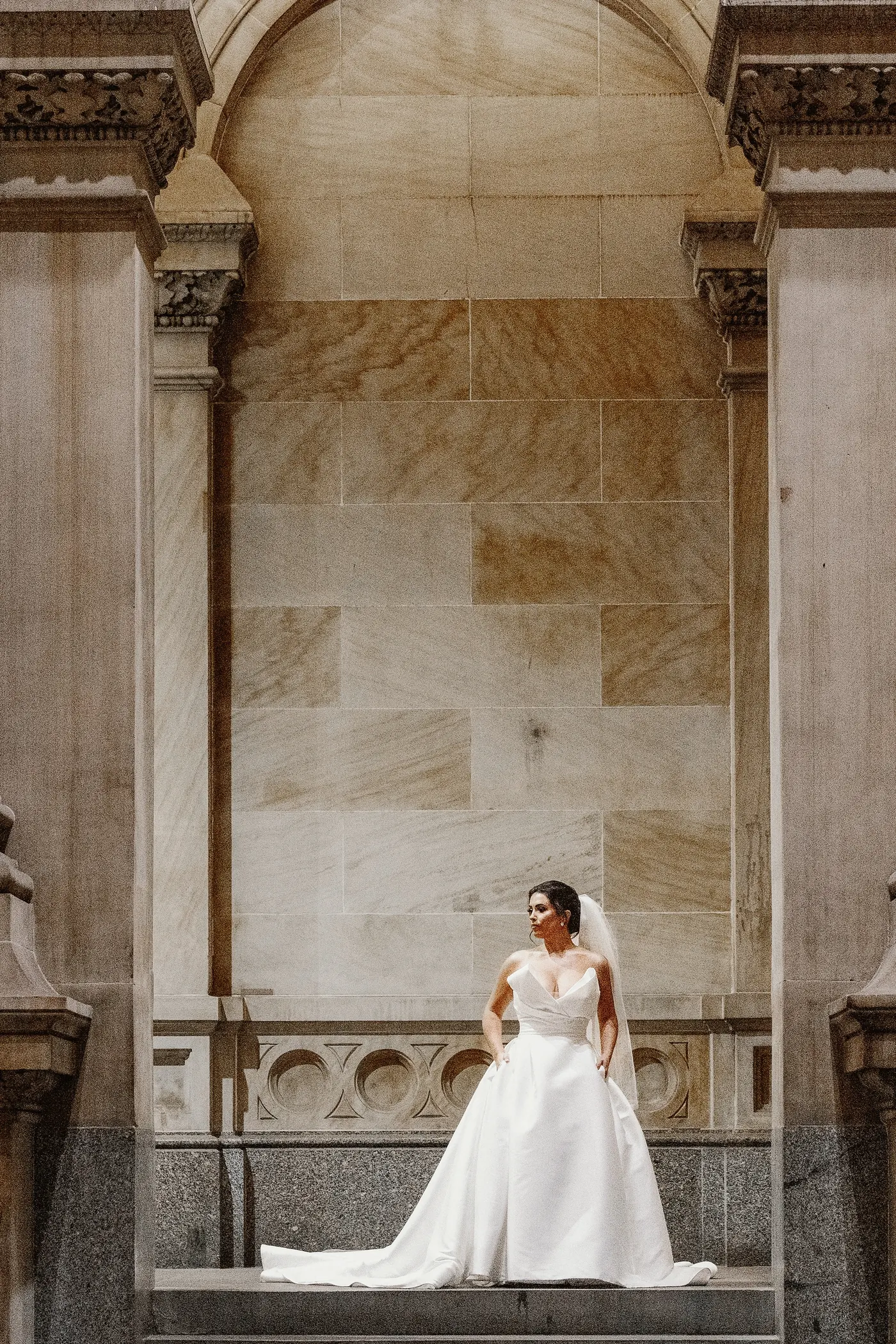 Celeste standing small beneath a grand stone arch at Philadelphia City Hall