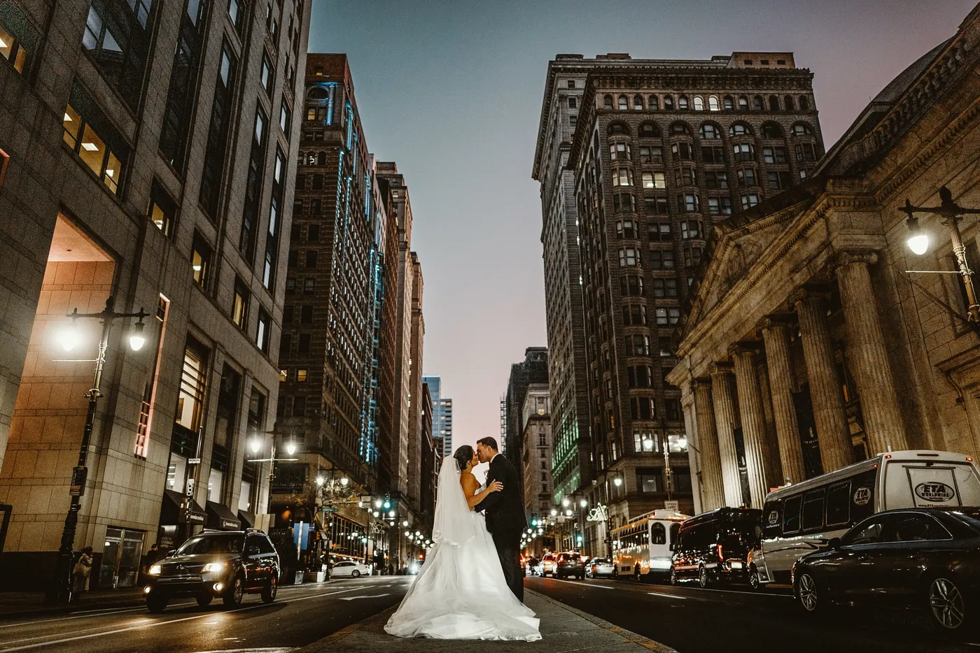 Branon and Celeste kissing in the middle of a city street at dusk in Center City Philadelphia