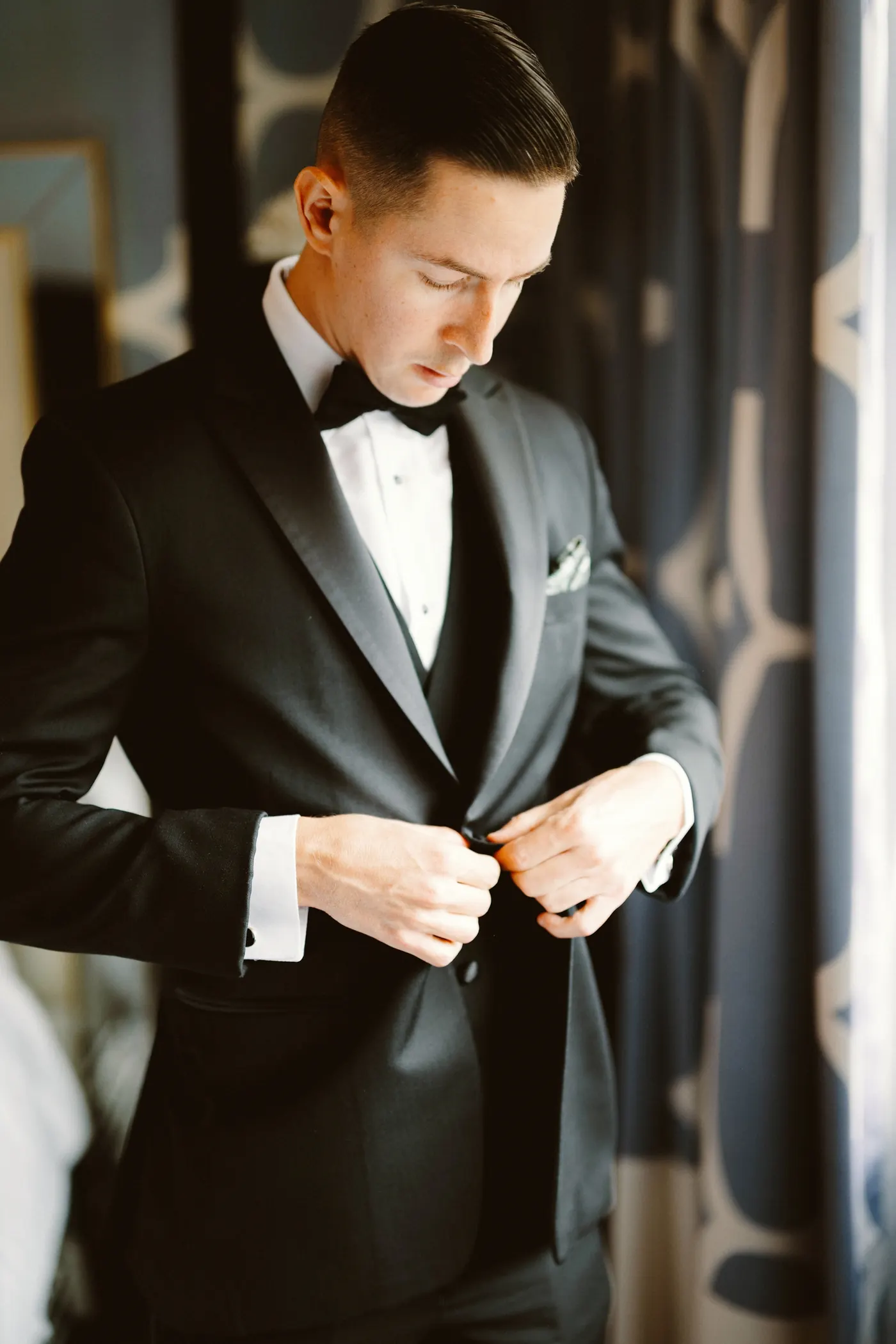 Chris buttoning his tuxedo jacket while getting ready