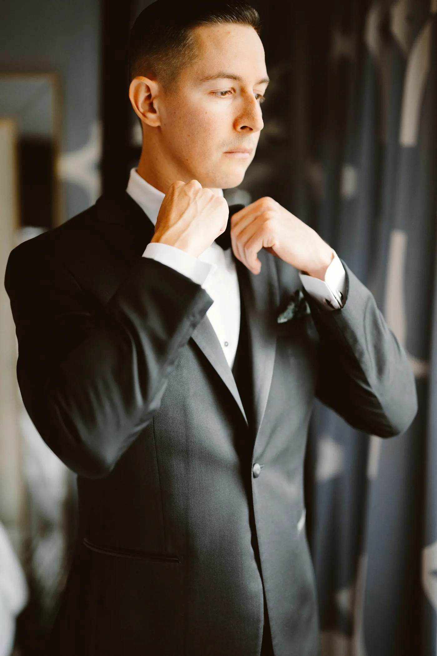 Chris adjusting his bow tie by the window