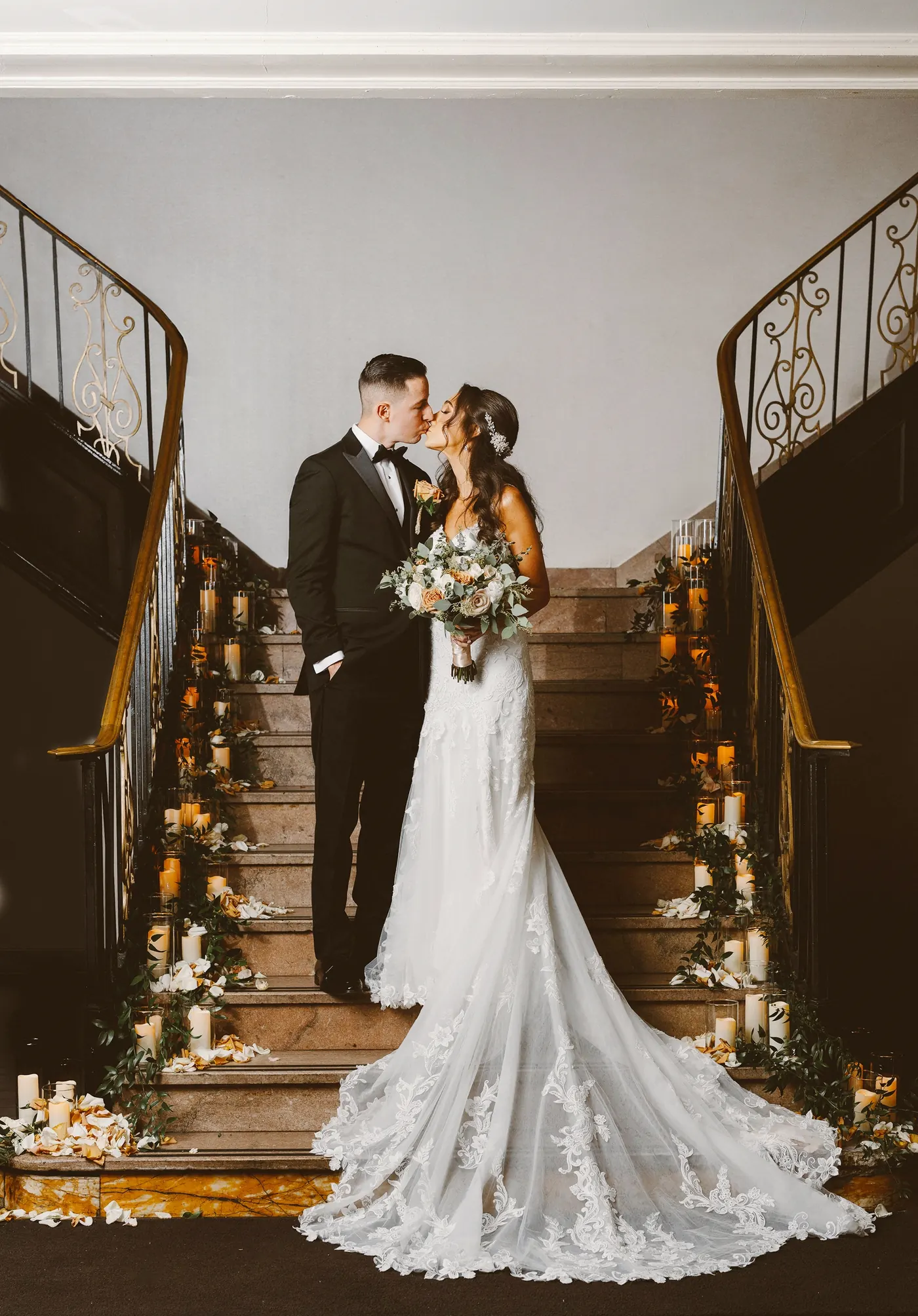 Chris and Danielle kissing at the foot of the grand staircase at Cescaphe Ballroom at the Ben in Philadelphia