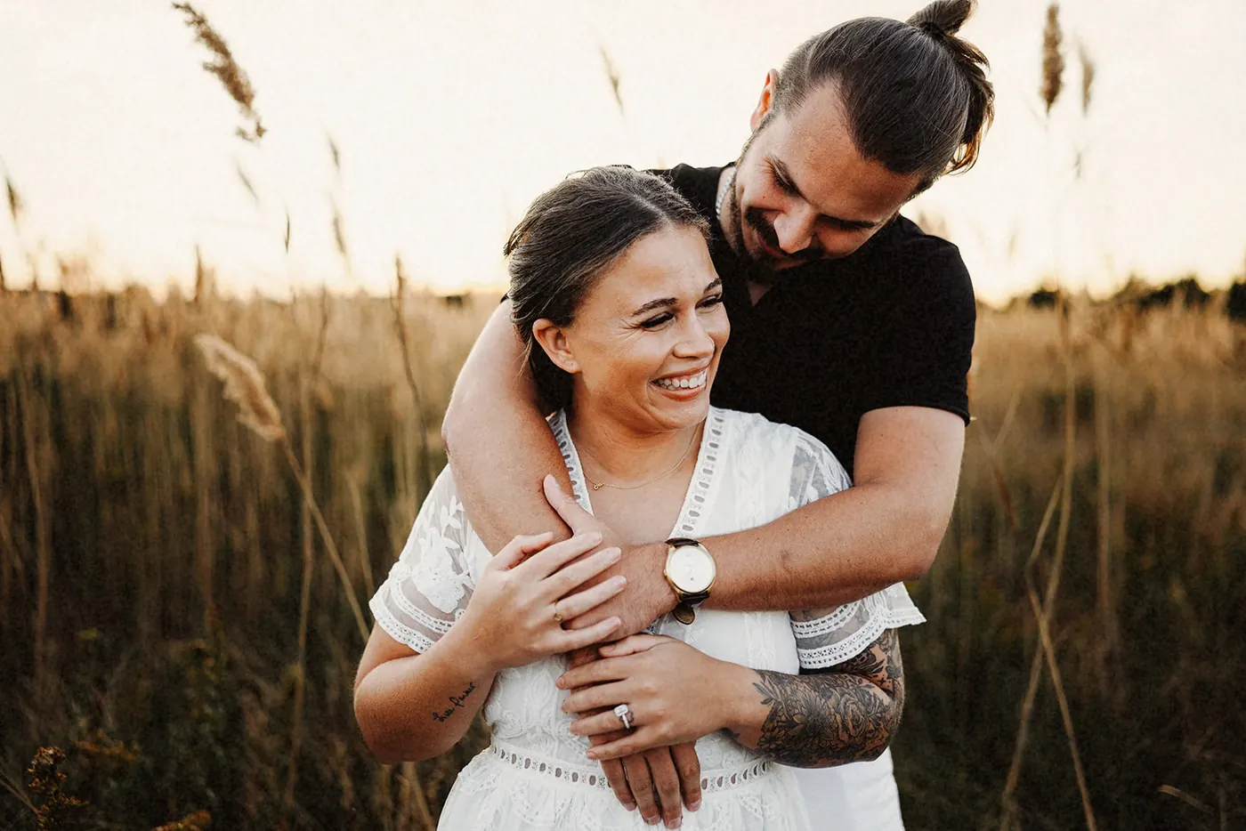 Dan hugging Madison from behind as she laughs in the tall grass near Barnegat Lighthouse on Long Beach Island, NJ