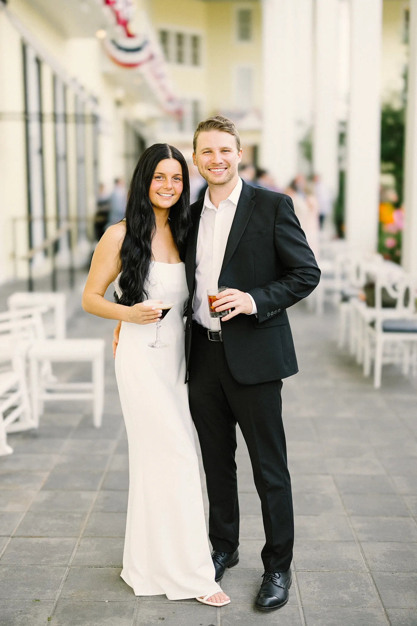 Mason and Morgan standing together with drinks on the porch of Congress Hall in Cape May, NJ