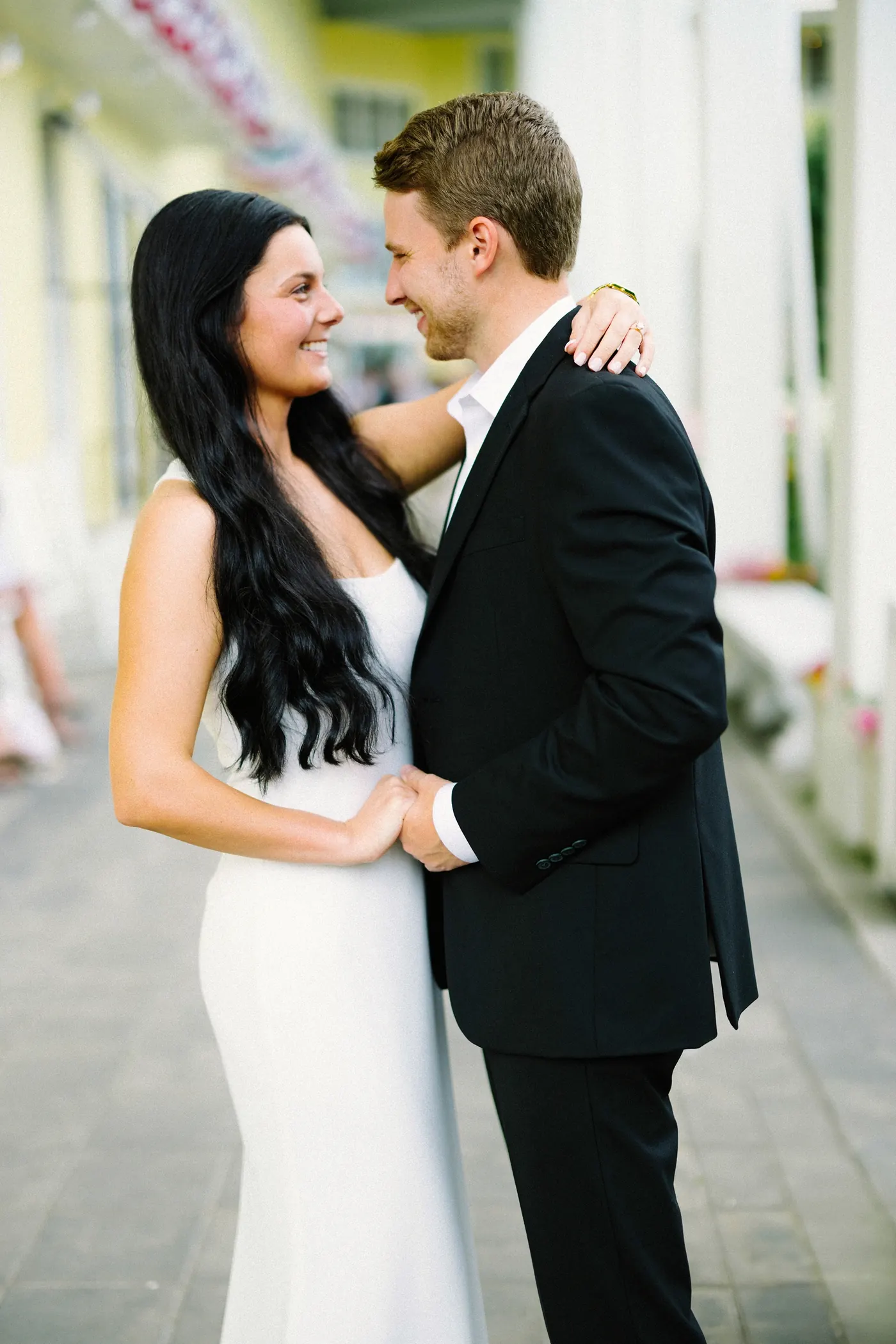 Mason and Morgan embracing on the porch of Congress Hall in Cape May, NJ, beneath flag bunting