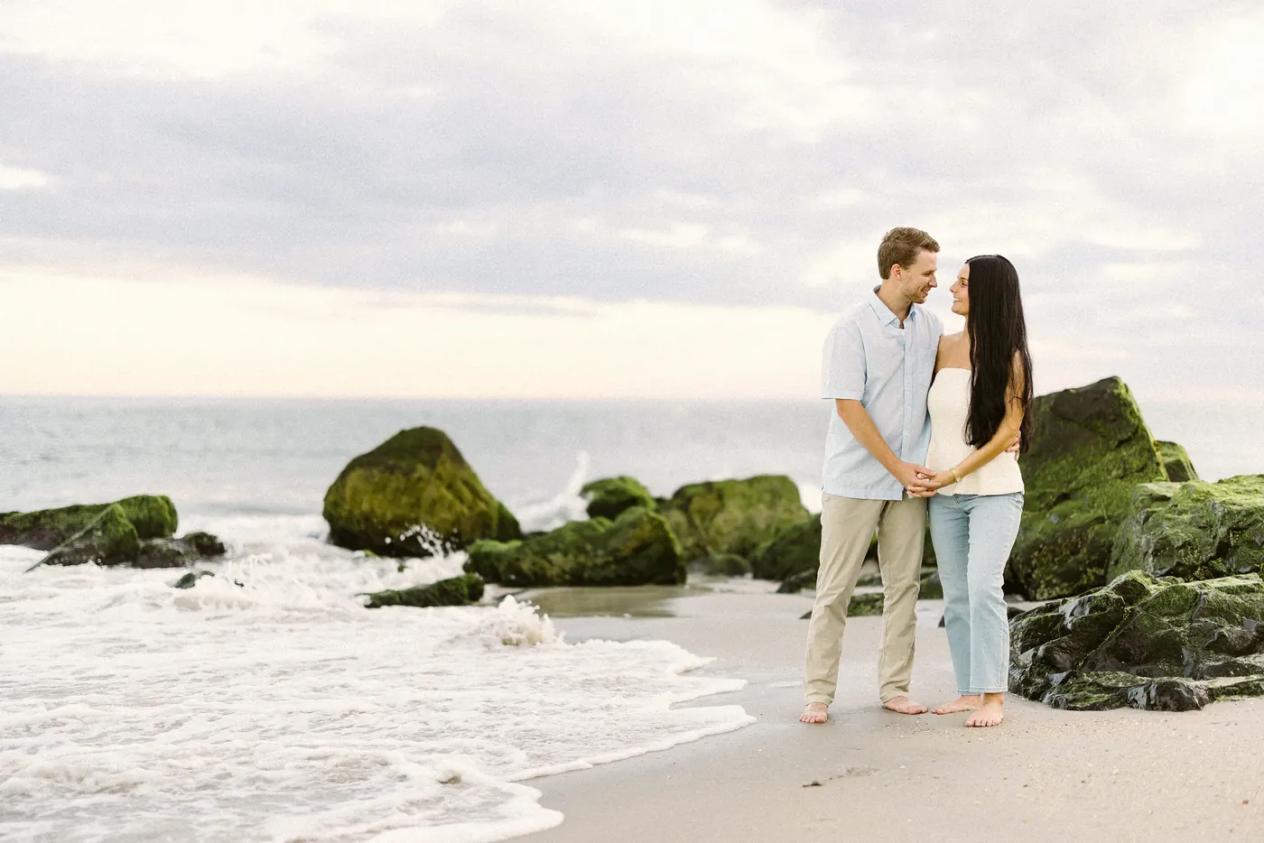 Mason and Morgan standing by the rocks at the water's edge in Cape May, NJ, near Congress Hall