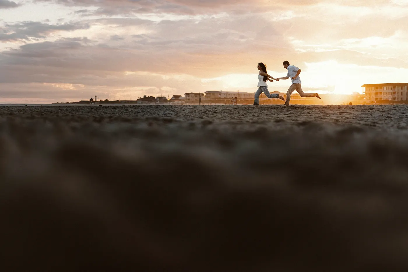 Mason and Morgan running hand in hand along the beach at sunset