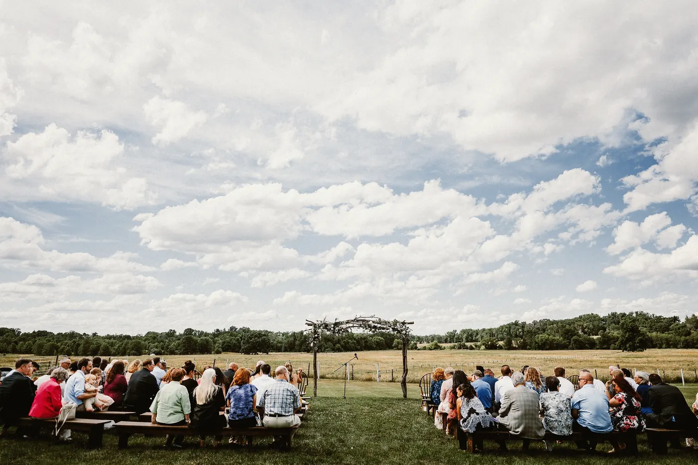Guests seated on benches for the outdoor ceremony in an open field at Johnson's Locust Hall Farm in Jobstown, NJ