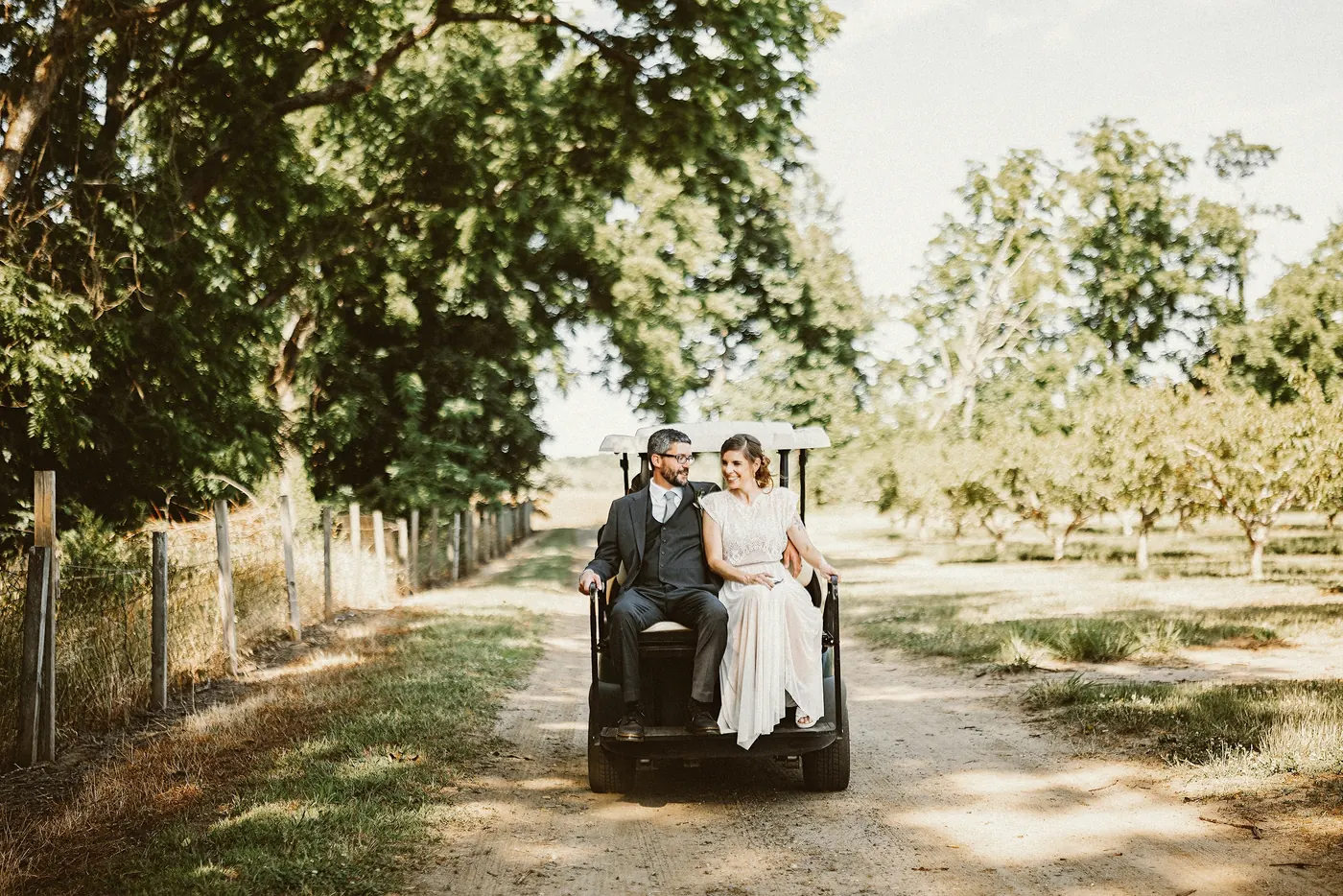 Matt and Erica riding a cart down a tree-lined lane through the orchard at Johnson's Locust Hall Farm in Jobstown, NJ