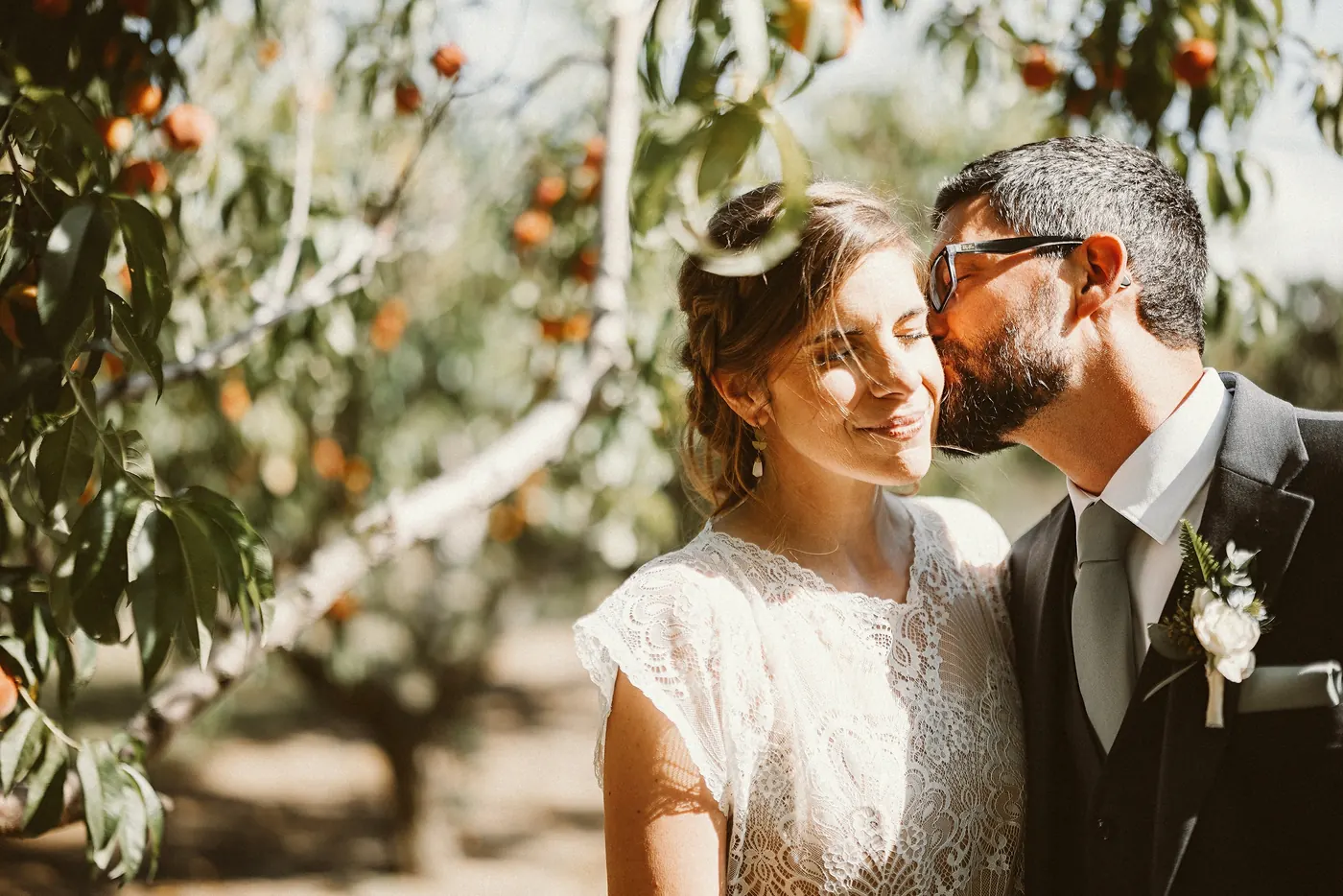 Matt kissing Erica on the cheek under the peach trees at Johnson's Locust Hall Farm in Jobstown, NJ