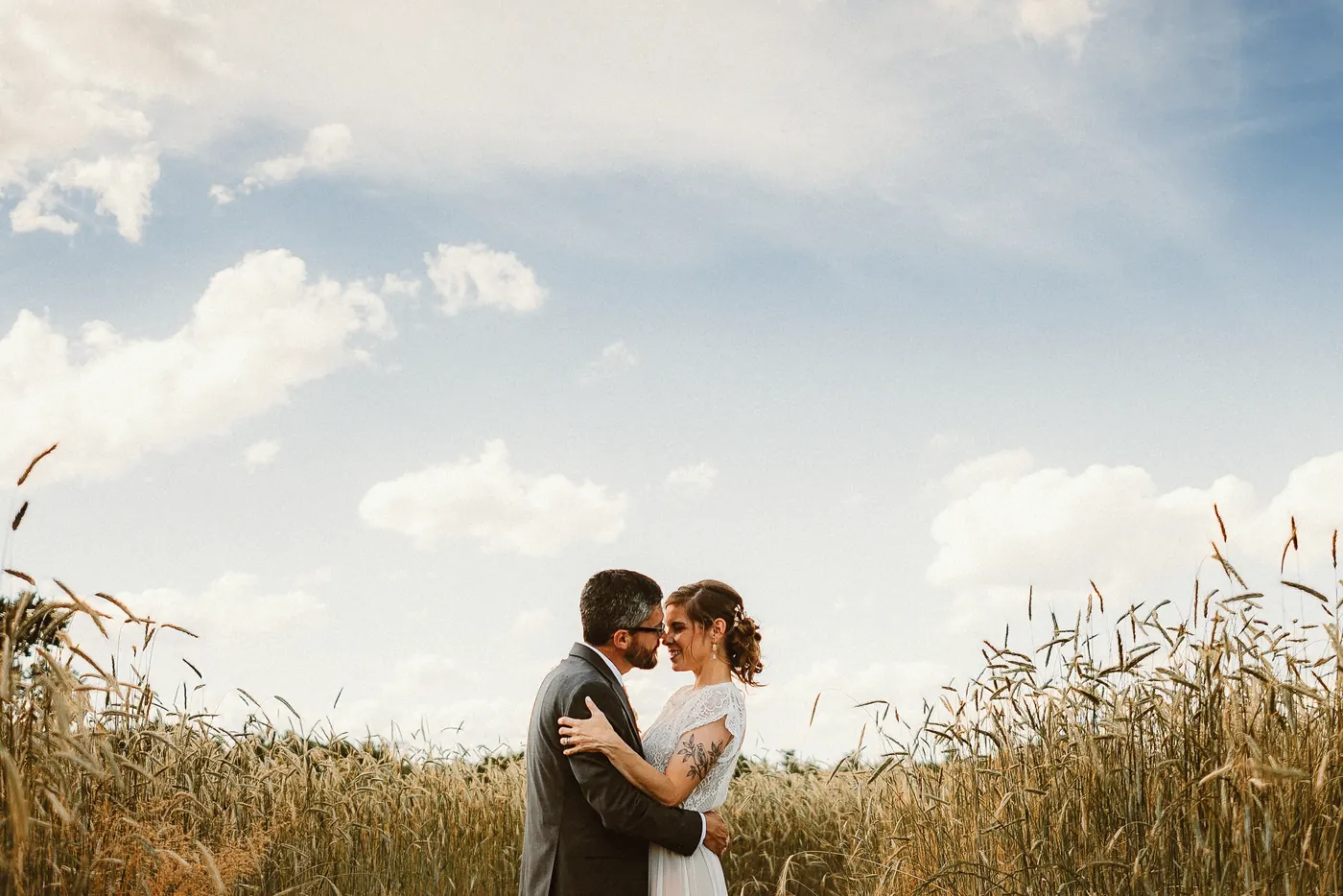 Matt and Erica embracing in a grain field under a big blue sky at Johnson's Locust Hall Farm in Jobstown, NJ
