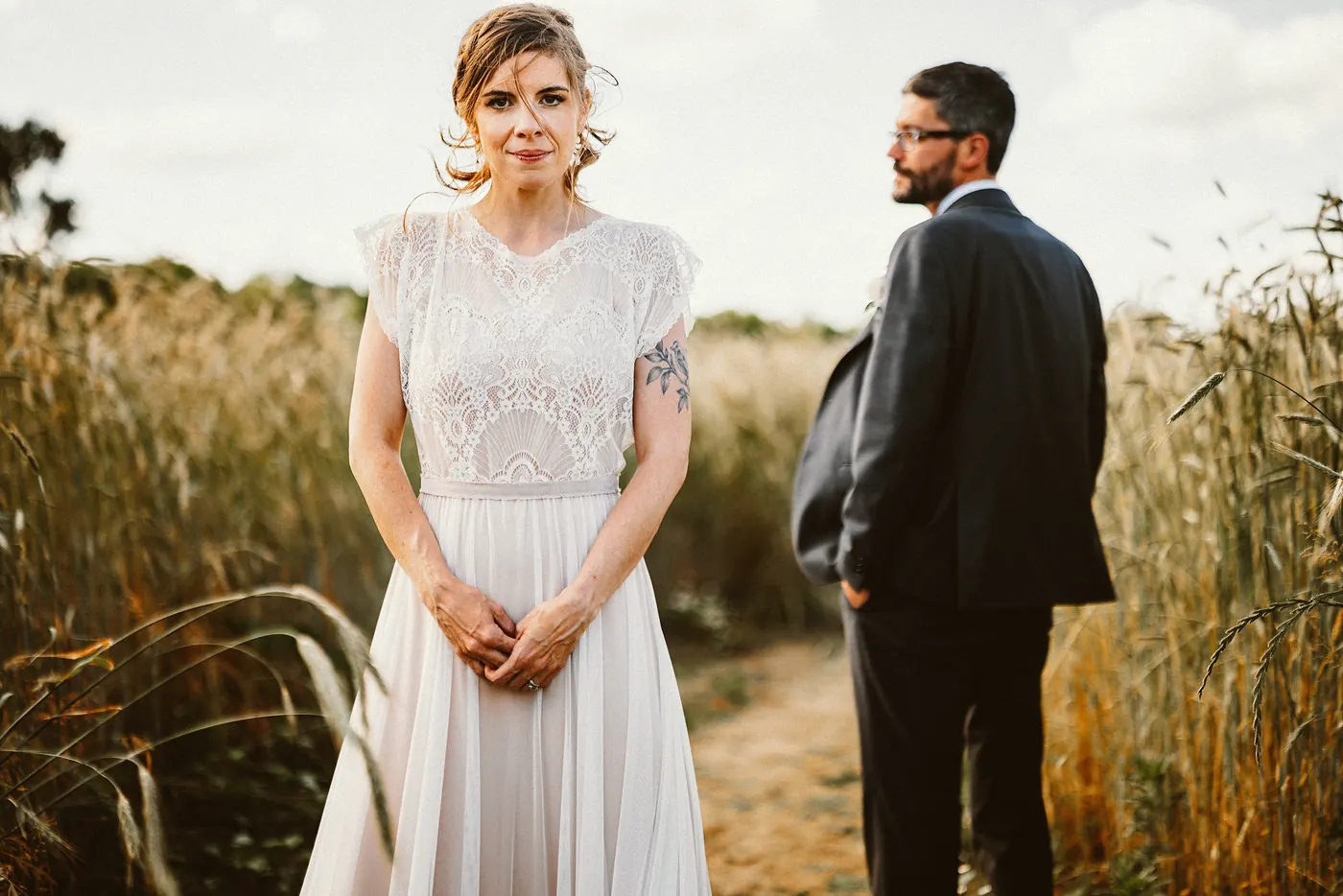 Erica in her lace wedding dress on a path through the grain field with Matt beside her at Johnson's Locust Hall Farm in Jobstown, NJ