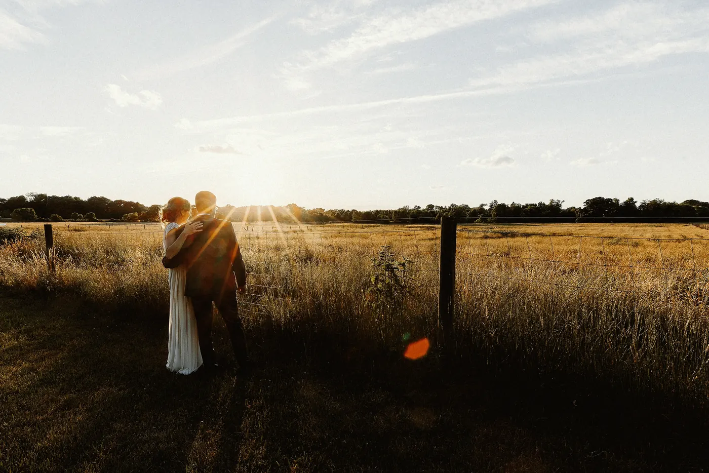 Matt and Erica embracing in the field as the sun sets behind them at Johnson's Locust Hall Farm in Jobstown, NJ