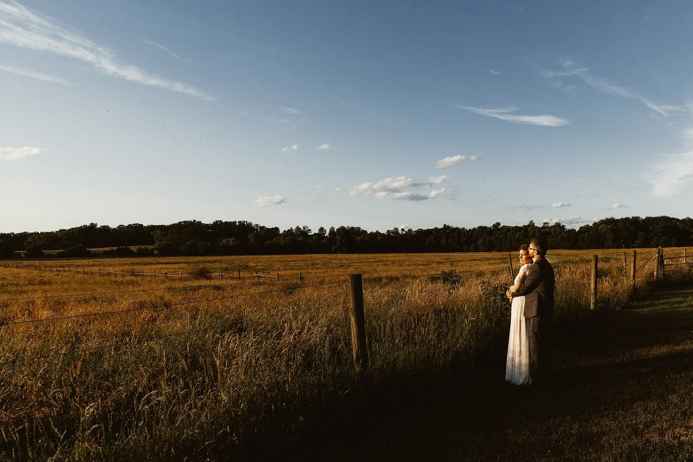 Matt and Erica small in a wide open field at dusk at Johnson's Locust Hall Farm in Jobstown, NJ