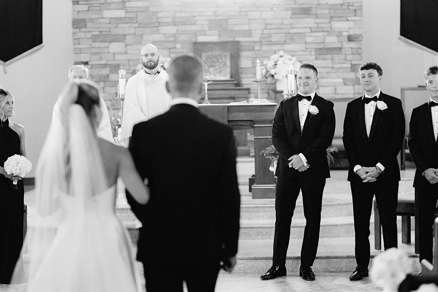 Steve and his groomsmen watching Madison walk toward the altar at Saint Charles Borromeo Church in Cinnaminson, NJ, in black and white