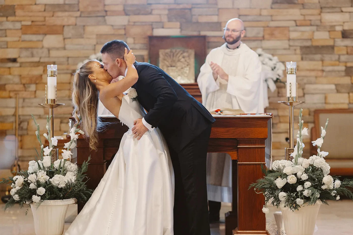 Steve dipping Madison for their first kiss as the priest applauds