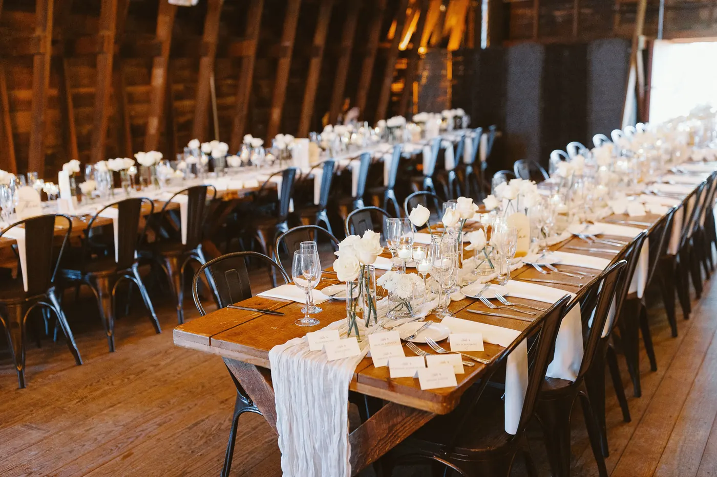 Long farm tables set for the reception inside the barn at Bishop Farmstead