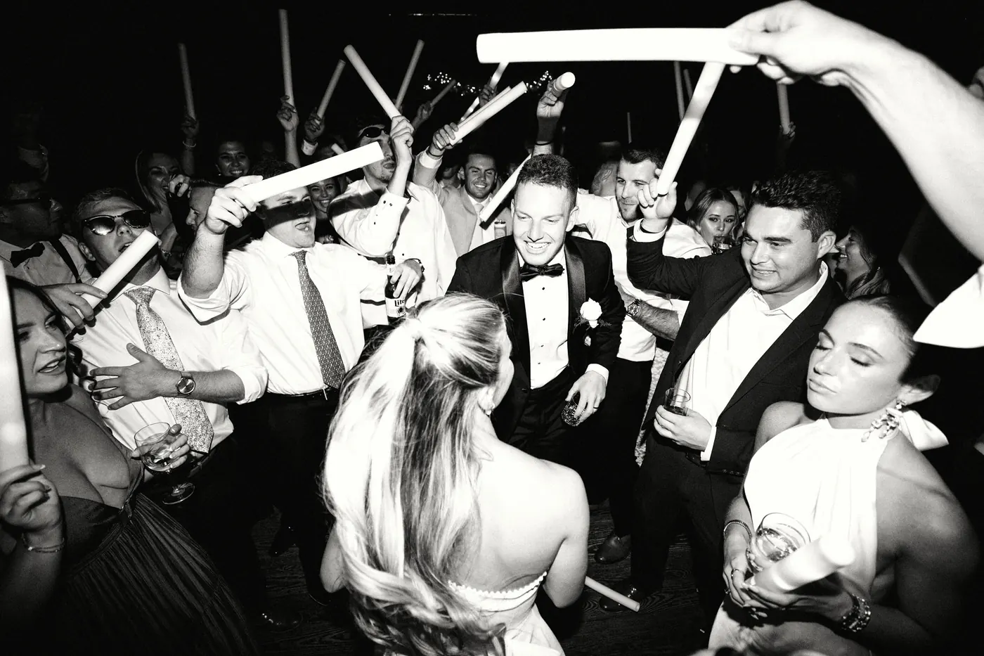 Guests raising light sticks around the newlyweds, in black and white